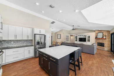 Eat-in kitchen - large modern u-shaped light wood floor and brown floor eat-in kitchen idea in Louisville with a double-bowl sink, shaker cabinets, white cabinets, quartz countertops, gray backsplash, stainless steel appliances, an island and white countertops