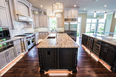 Inspiration for a large transitional kitchen in Baltimore with a farmhouse sink, recessed-panel cabinets, stone tile splashback, stainless steel appliances, dark hardwood floors and multiple islands.