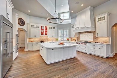 Photo of a large traditional separate kitchen in Sacramento with shaker cabinets, white cabinets, marble benchtops, brown splashback, stainless steel appliances, with island and brown floor.
