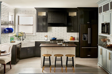 Open concept kitchen - traditional u-shaped open concept kitchen idea with shaker cabinets, black cabinets, marble countertops, white backsplash, ceramic backsplash, black appliances and an island
