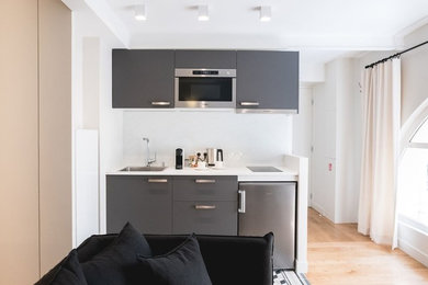 Idées déco pour une petite cuisine ouverte linéaire contemporaine avec aucun îlot, un évier 1 bac, un placard à porte plane, des portes de placard grises, un plan de travail en stratifié, une crédence blanche, un électroménager en acier inoxydable, un sol gris, un plan de travail blanc et un sol en carrelage de céramique.