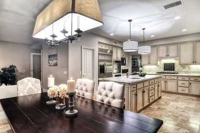 Large elegant u-shaped travertine floor kitchen pantry photo in Orange County with a double-bowl sink, raised-panel cabinets, beige cabinets, marble countertops, beige backsplash, stone tile backsplash, stainless steel appliances and an island