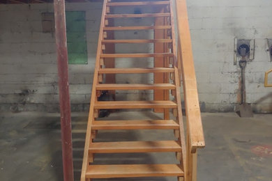 Imagen de escalera recta urbana grande con escalones de madera, contrahuellas de madera y barandilla de madera