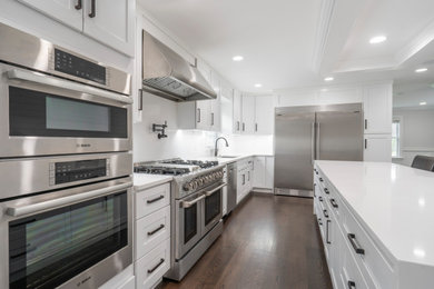 Mid-sized transitional single-wall dark wood floor, brown floor and tray ceiling eat-in kitchen photo in Philadelphia with a drop-in sink, flat-panel cabinets, white cabinets, marble countertops, white backsplash, marble backsplash, stainless steel appliances, an island and white countertops