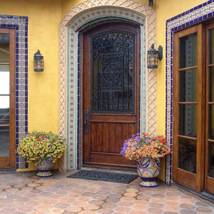 Inspiration pour une porte d'entrée bohème avec un mur jaune, un sol en carreau de terre cuite, une porte simple et une porte en bois brun.