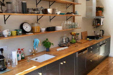 This is an example of a medium sized single-wall kitchen/diner in Dublin with a built-in sink, shaker cabinets, wood worktops and an island.