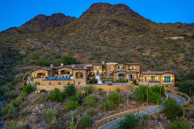 Inspiration for a huge mediterranean brown split-level brick house exterior remodel in Phoenix with a brown roof