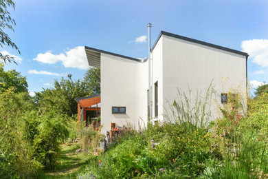 Modernes Haus mit Putzfassade, weißer Fassadenfarbe, Pultdach, Blechdach und schwarzem Dach in Sonstige