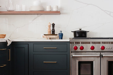 バーミングハムにある広いおしゃれなキッチン (エプロンフロントシンク、シェーカースタイル扉のキャビネット、青いキャビネット、クオーツストーンカウンター、白いキッチンパネル、クオーツストーンのキッチンパネル、シルバーの調理設備、淡色無垢フローリング、白いキッチンカウンター) の写真