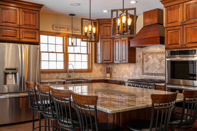 Example of a large classic l-shaped medium tone wood floor, brown floor and vaulted ceiling kitchen pantry design in New York with a farmhouse sink, raised-panel cabinets, dark wood cabinets, quartz countertops, beige backsplash, mosaic tile backsplash, stainless steel appliances, an island and multicolored countertops