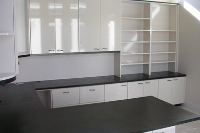 Diseño de despacho actual de tamaño medio sin chimenea con paredes blancas, suelo de cemento y escritorio empotrado