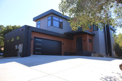 Modelo de fachada de casa negra grande de dos plantas con revestimientos combinados y tejado plano