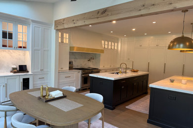 Kitchen - large transitional light wood floor kitchen idea in Philadelphia with white cabinets, quartz countertops, paneled appliances, two islands and white countertops