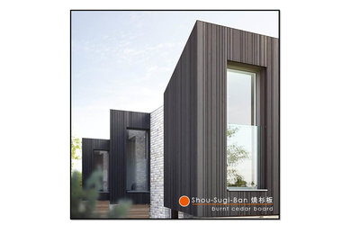 Large and black contemporary two floor house exterior with wood cladding and a flat roof.