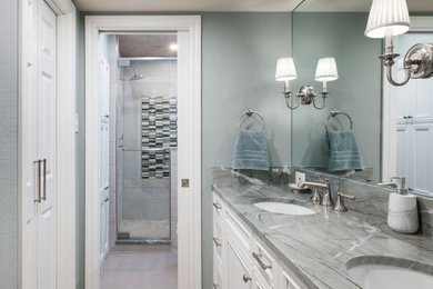 Example of a mid-sized trendy master gray tile and porcelain tile porcelain tile, gray floor and double-sink bathroom design in Dallas with white cabinets, a two-piece toilet, blue walls, an undermount sink, quartzite countertops, a hinged shower door, multicolored countertops and a built-in vanity