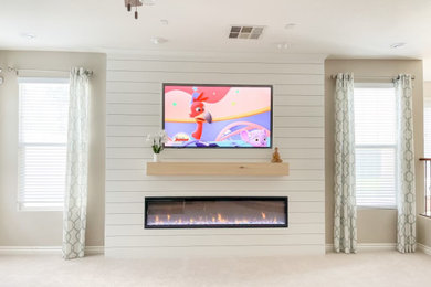 ラスベガスにある高級な小さなトラディショナルスタイルのおしゃれなLDK (ベージュの壁、カーペット敷き、標準型暖炉、塗装板張りの暖炉まわり、壁掛け型テレビ、ベージュの床、塗装板張りの壁) の写真