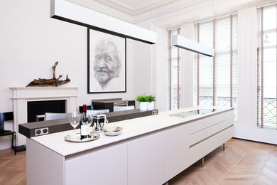 This is an example of a large contemporary kitchen in Edinburgh with flat-panel cabinets, white cabinets, medium hardwood floors and with island.