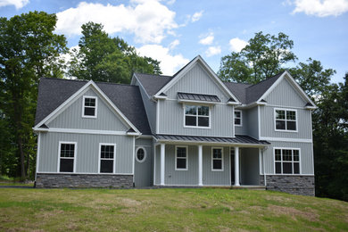 Example of a large blue two-story house exterior design with a shingle roof and a gray roof