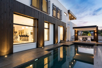 Inspiration for a large contemporary backyard custom-shaped pool in Melbourne with concrete pavers.