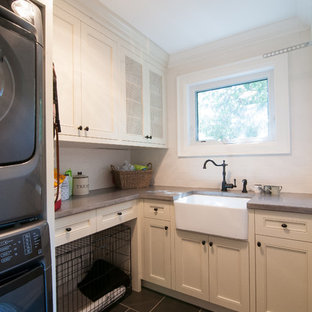 Modelo de cuarto de lavado en L, campestre, pequeño, con lavadora y secadora apiladas, fregadero sobremueble, armarios estilo shaker, puertas de armario blancas, encimera de cuarzo compacto, paredes blancas y suelo de baldosas de cerámica