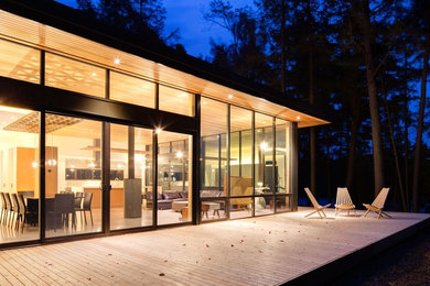 Example of a mid-sized mid-century modern backyard deck design in Toronto with a roof extension
