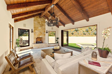 Example of a tuscan light wood floor and beige floor living room design in Los Angeles with white walls, a standard fireplace and a stone fireplace