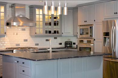 Mid-sized trendy l-shaped dark wood floor eat-in kitchen photo in Edmonton with an undermount sink, raised-panel cabinets, white cabinets, white backsplash, ceramic backsplash, stainless steel appliances and an island