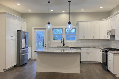 Example of a farmhouse u-shaped dark wood floor and brown floor eat-in kitchen design in Chicago with a double-bowl sink, shaker cabinets, white cabinets, granite countertops, white backsplash, cement tile backsplash, stainless steel appliances and an island