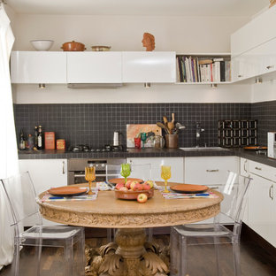 Exemple d'une cuisine américaine tendance en L de taille moyenne avec un placard à porte plane, des portes de placard blanches, une crédence noire et un sol en bois foncé.