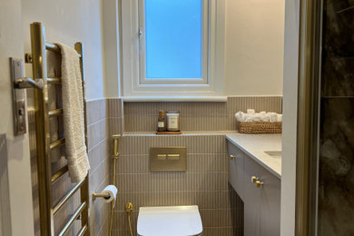 This is an example of a medium sized modern cloakroom in Other with flat-panel cabinets, beige cabinets, a wall mounted toilet, beige tiles, porcelain tiles, white walls, porcelain flooring, a built-in sink, quartz worktops, beige floors, white worktops and a built in vanity unit.