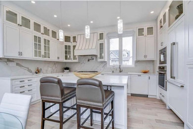 Inspiration for a mid-sized transitional u-shaped light wood floor and beige floor eat-in kitchen remodel in Toronto with an undermount sink, recessed-panel cabinets, white cabinets, quartz countertops, white backsplash, quartz backsplash, paneled appliances, an island and white countertops