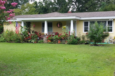Example of a mid-sized transitional yellow one-story stucco house exterior design in Other with a hip roof and a shingle roof