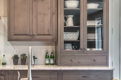 Example of a mid-sized mountain style single-wall medium tone wood floor open concept kitchen design in Other with a farmhouse sink, raised-panel cabinets, gray cabinets, granite countertops, white backsplash, ceramic backsplash, stainless steel appliances and an island