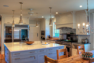Photo of a mid-sized transitional u-shaped open plan kitchen in Philadelphia with an undermount sink, beaded inset cabinets, white cabinets, quartz benchtops, grey splashback, porcelain splashback, stainless steel appliances, medium hardwood floors, with island, brown floor and white benchtop.