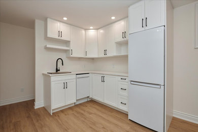 Small minimalist l-shaped vinyl floor and brown floor kitchen photo in Toronto with shaker cabinets, white cabinets, quartzite countertops, no island and white countertops