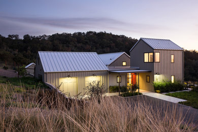Exemple d'une grande façade de maison grise nature en panneau de béton fibré et planches et couvre-joints à un étage avec un toit à deux pans, un toit en métal et un toit gris.