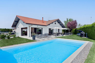 Foto de piscina actual rectangular en patio trasero con paisajismo de piscina y suelo de baldosas