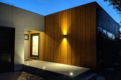 Modelo de fachada de casa marrón rural de tamaño medio de una planta con revestimiento de madera, tejado plano y tejado de metal