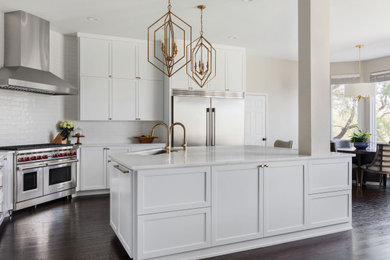 Design ideas for a large transitional l-shaped open plan kitchen in Austin with an undermount sink, shaker cabinets, white cabinets, quartz benchtops, white splashback, ceramic splashback, stainless steel appliances, dark hardwood floors, with island, brown floor and white benchtop.
