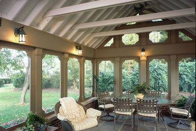 This is an example of a mid-sized stone back porch design in Cleveland with a roof extension.