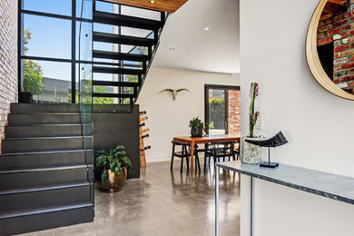 This is an example of a large industrial foyer in Newcastle - Maitland with multi-coloured walls, concrete floors, a single front door, a black front door and grey floor.