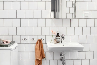 Small scandinavian master bathroom in Stockholm with flat-panel cabinets, white tile, porcelain tile, white walls, limestone floors and a wall-mount sink.