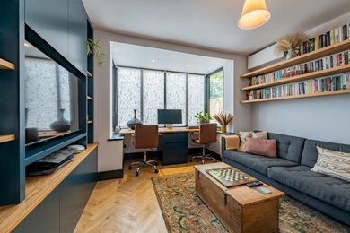 This is an example of a contemporary home office in Other with feature lighting, grey walls, medium hardwood flooring, a built-in desk and brown floors.