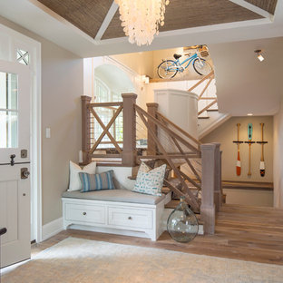 ミネアポリスの中サイズのダッチドアビーチスタイルのおしゃれな玄関ロビー (無垢フローリング、ベージュの壁、白いドア) の写真