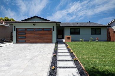 Example of a mid-sized trendy green one-story stucco house exterior design in San Francisco with a shingle roof and a black roof