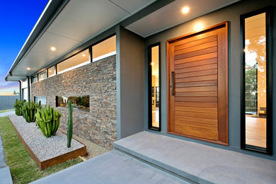 Inspiration for a midcentury split-level house exterior in Sunshine Coast with stone veneer.
