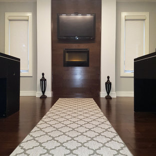 Inspiration for a medium sized modern study in Toronto with grey walls, dark hardwood flooring, a standard fireplace, a wooden fireplace surround, a freestanding desk and brown floors.