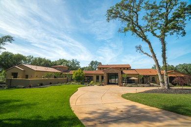 Large trendy yellow one-story stucco exterior home photo in Sacramento with a tile roof