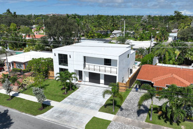 Example of a trendy white two-story house exterior design in Miami with a white roof