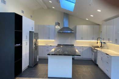 Eat-in kitchen - large modern u-shaped ceramic tile, black floor and vaulted ceiling eat-in kitchen idea in Los Angeles with a farmhouse sink, flat-panel cabinets, white cabinets, marble countertops, porcelain backsplash, stainless steel appliances, an island, white countertops and white backsplash